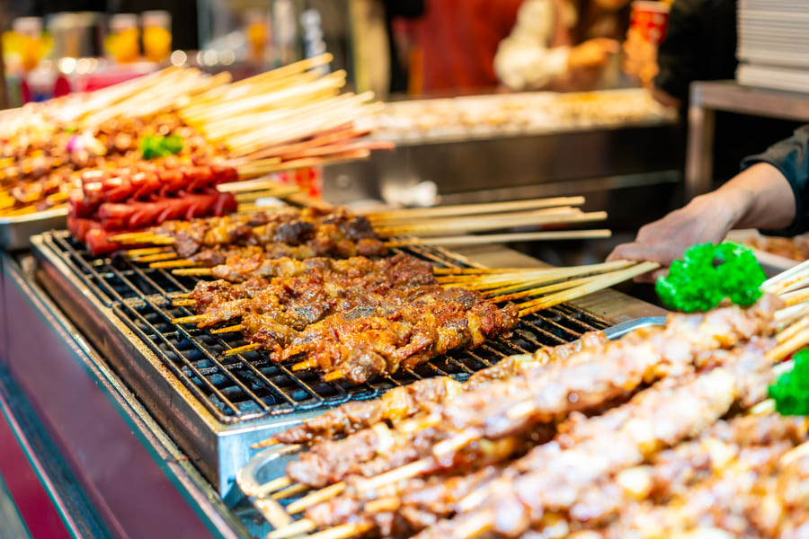 Variadas brochetas asándose en una parrilla.